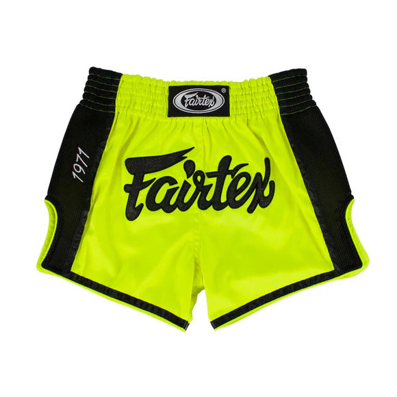 Bright yellow Muay Thai shorts with black trim and Fairtex logo on a white background