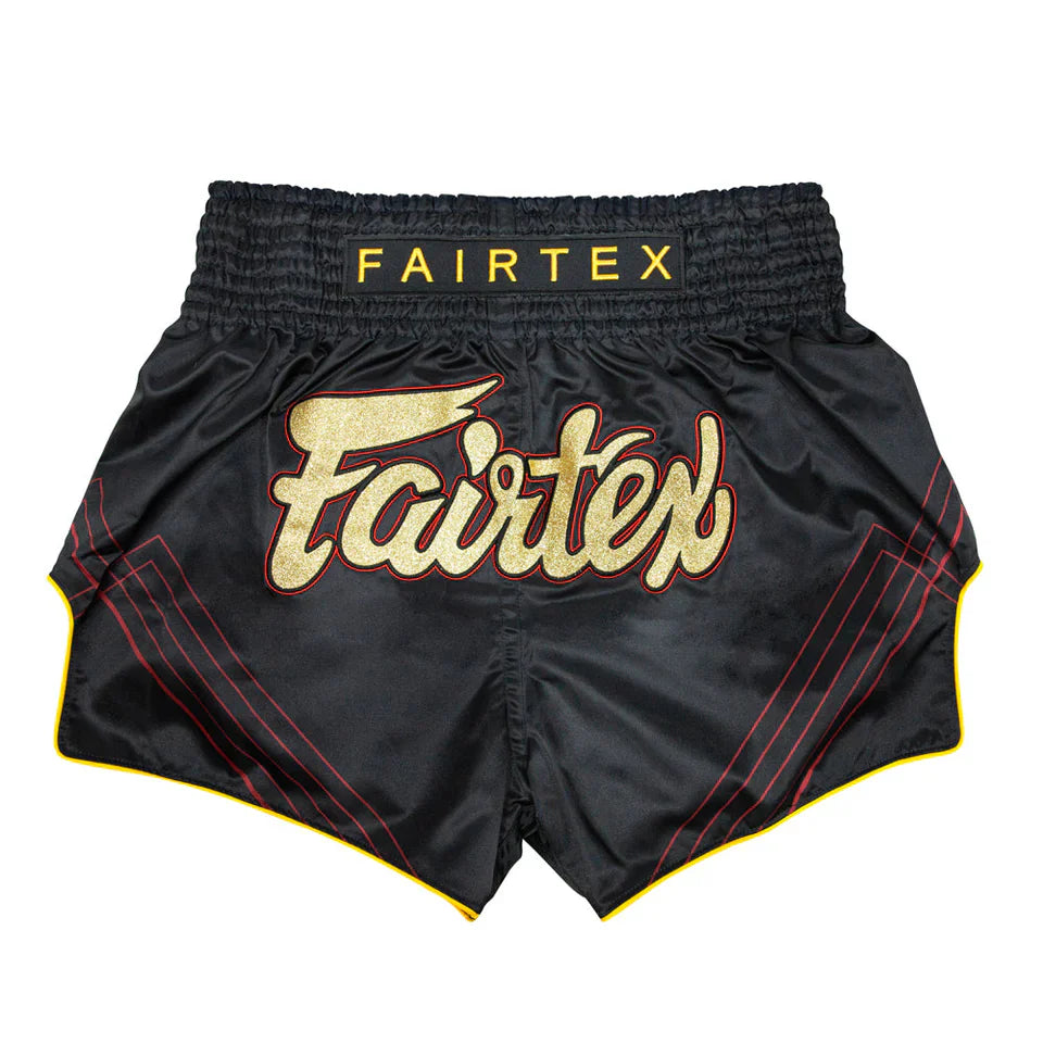 Black Fairtex Muay Thai shorts with gold and red accents on a white background