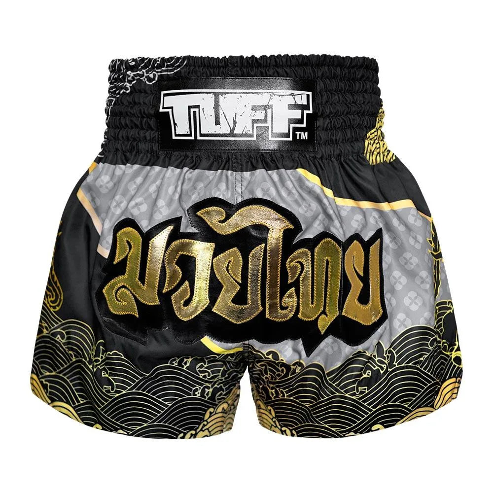 Black and gold Muay Thai shorts with 'TUFF' branding on a white background