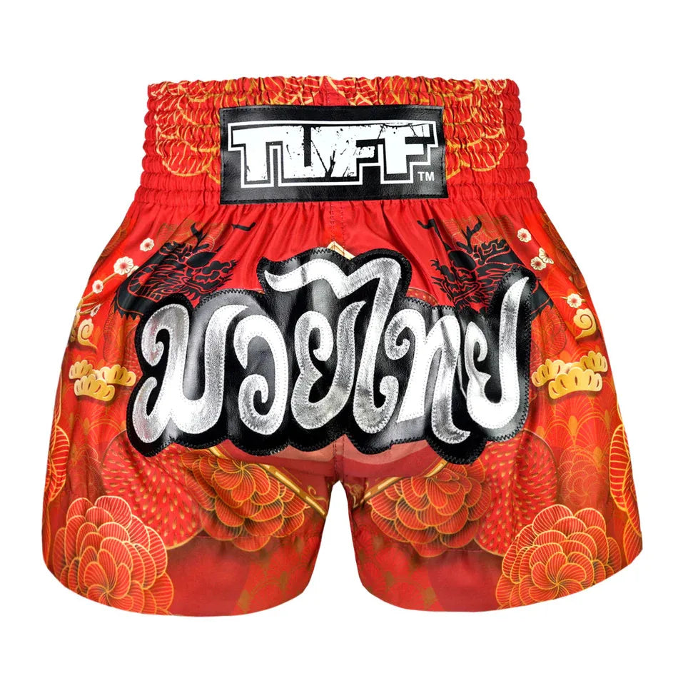 Red Muay Thai boxing shorts with intricate designs and 'TUFF' branding on a white background