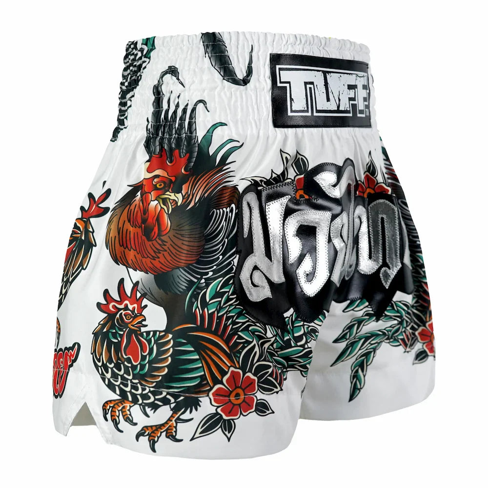 White Muay Thai shorts with rooster and floral tattoos and a visible brand logo on a white background