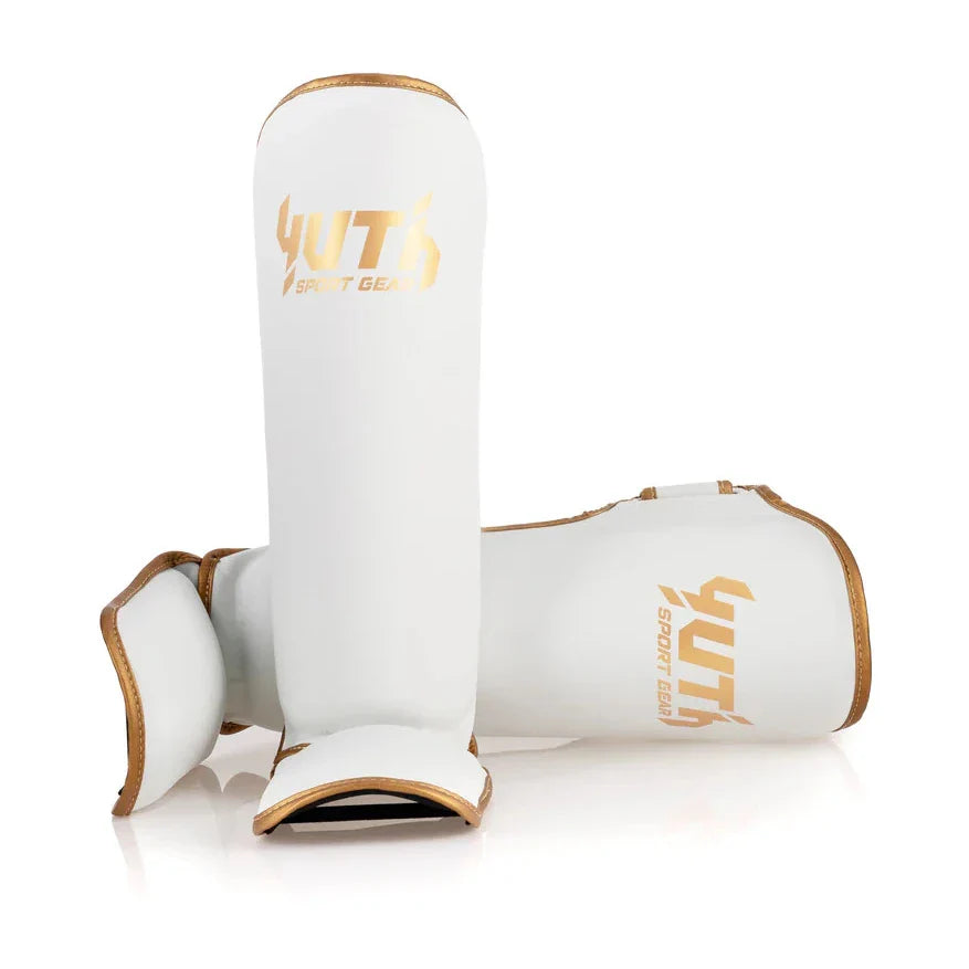 White shin guards with gold accents and 'YUTH' branding on a white background