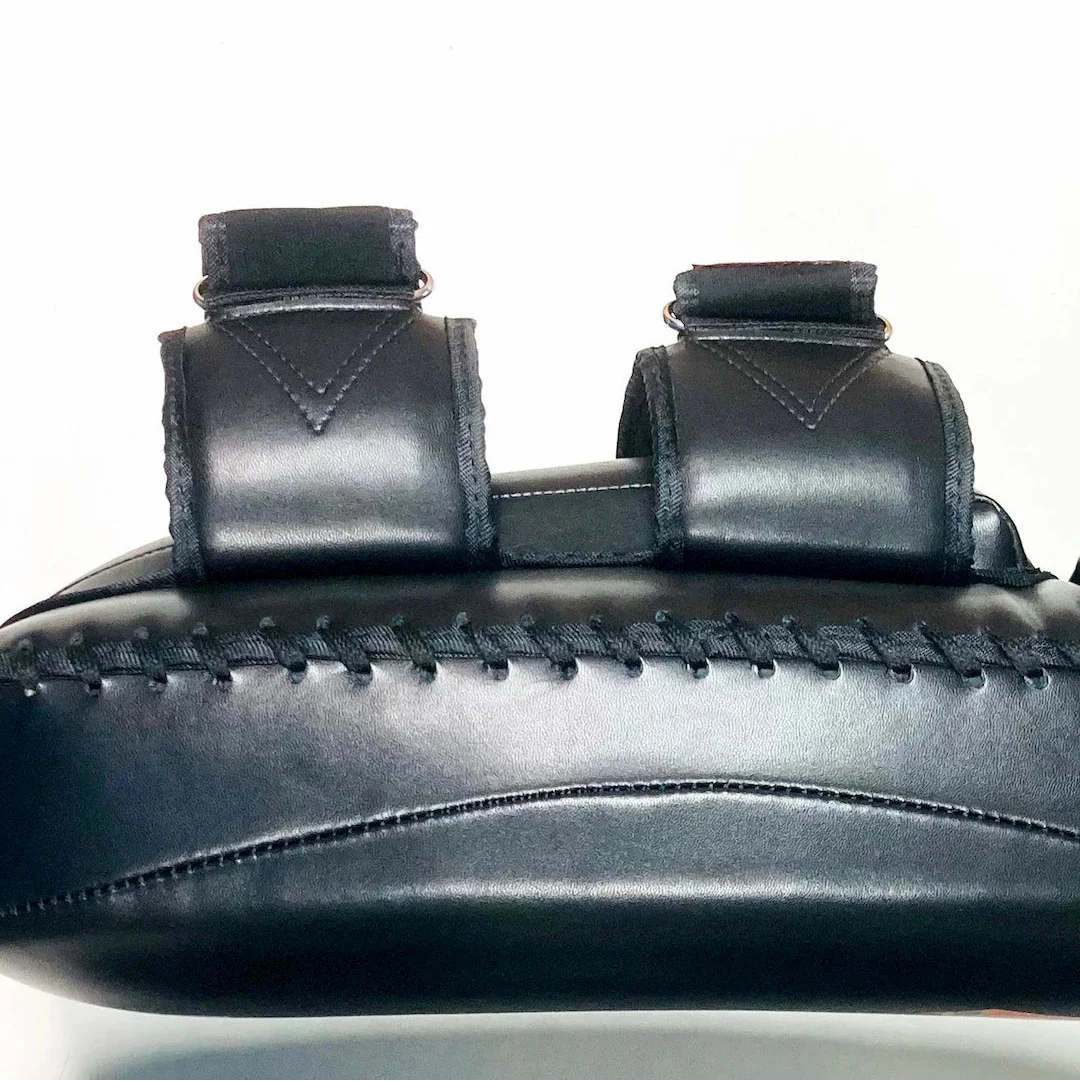 Close-up of a black leather Thai Pad with stitching details on a white background