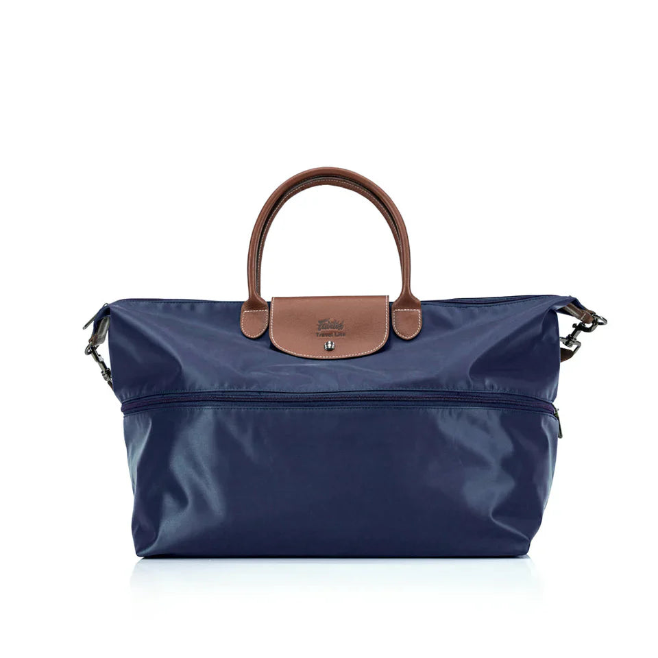 Navy blue handbag with brown leather handle and flap on a white background
