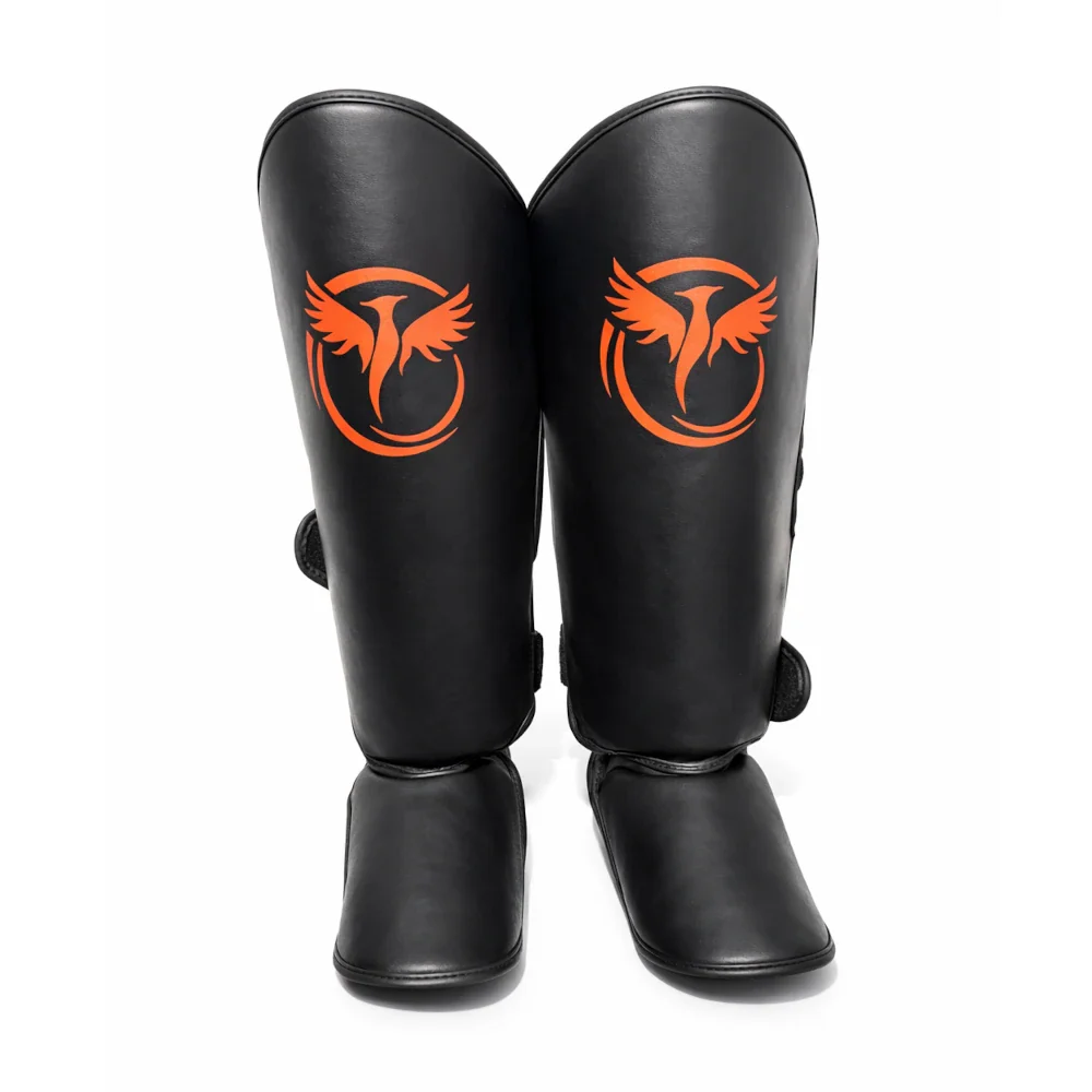 Black shin guards with orange logo on a white background