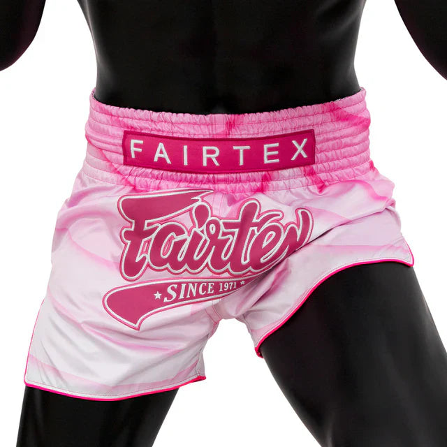 Pink and white Fairtex Muay Thai shorts on a black mannequin with a white background