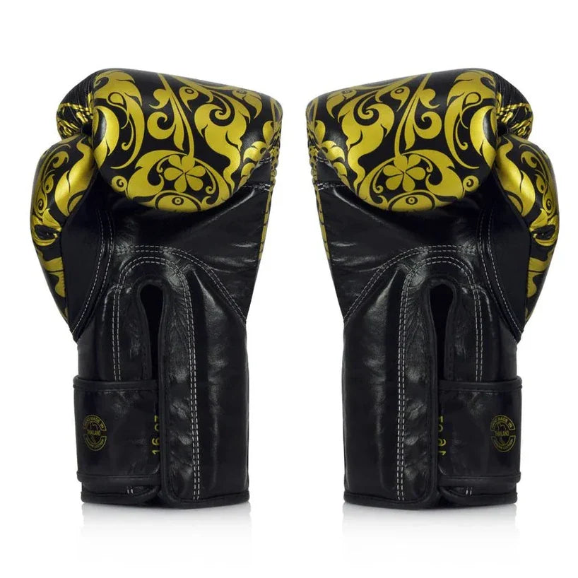 Black boxing gloves with gold patterns on a white background