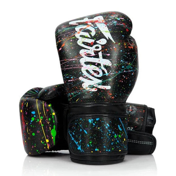 Black boxing gloves with colorful splatter design and 'Fairtex' branding on a white background