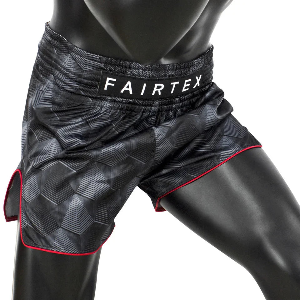 Black patterned Muay Thai shorts with 'Fairtex' branding on a mannequin.