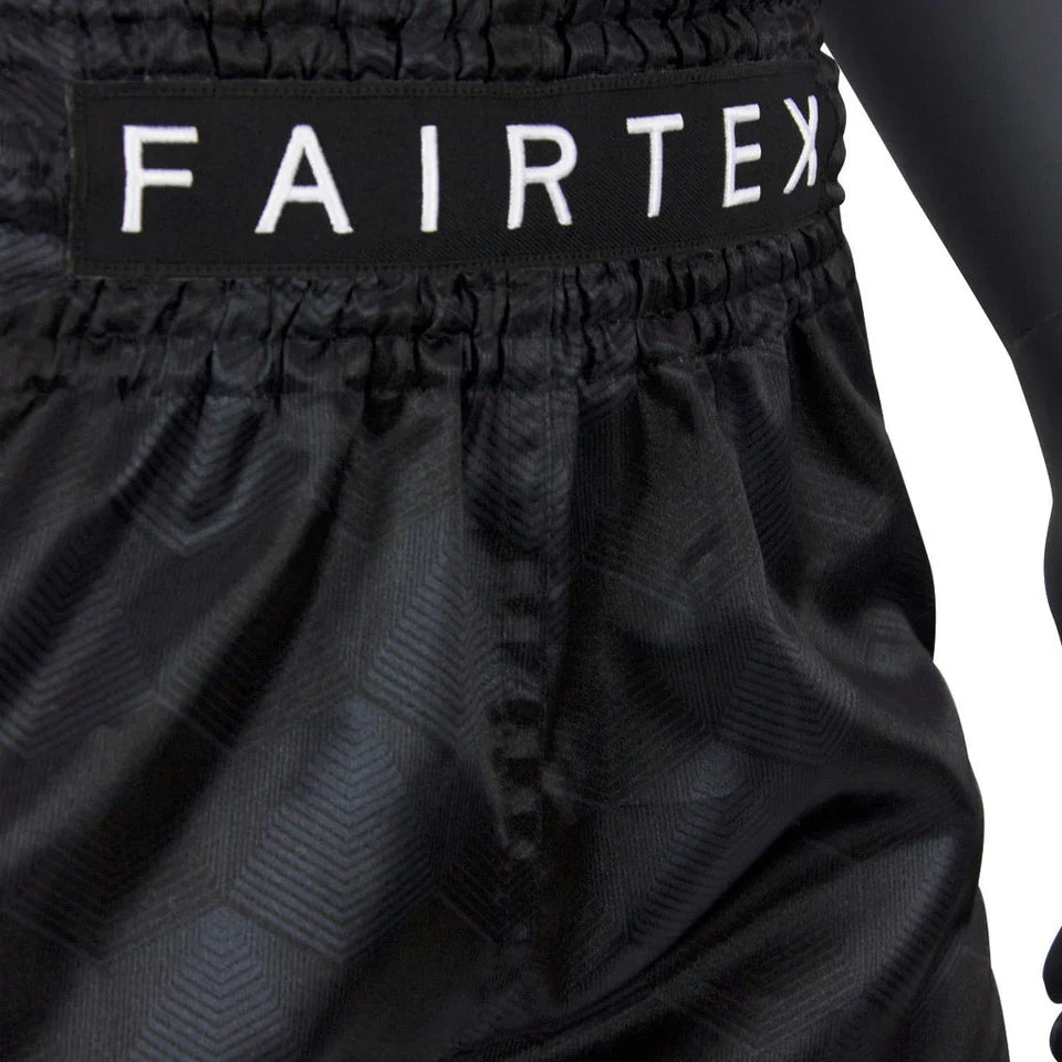 Black Muay Thai shorts with 'FAIRTEX' branding on a white background