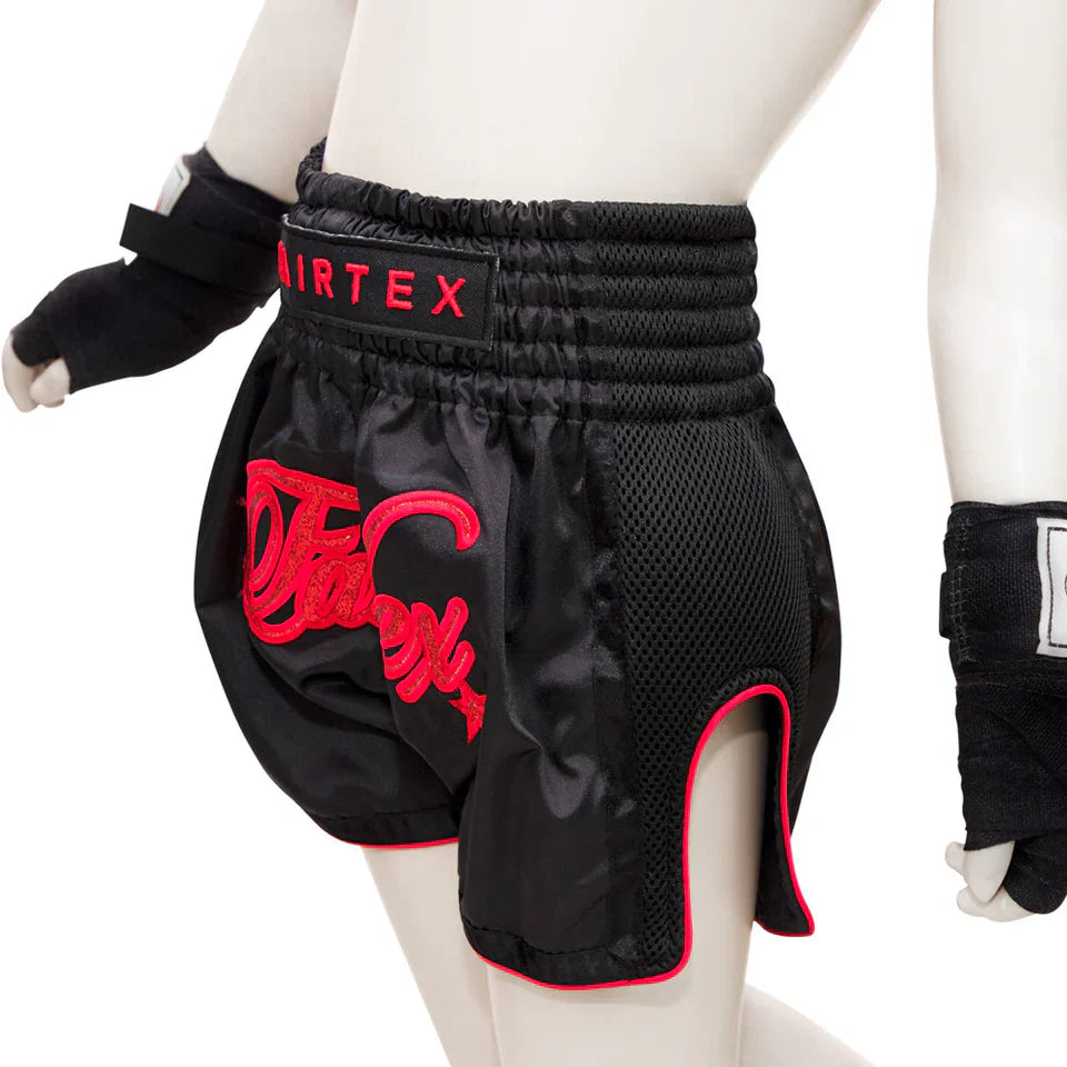 Black boxing shorts with red branding on a mannequin, wearing black gloves.