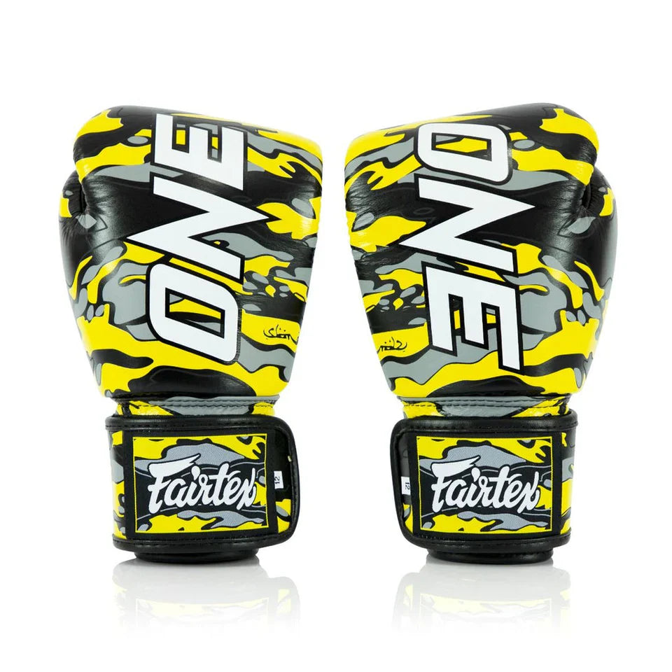 Pair of yellow and black boxing gloves with 'ONE' and 'Fairtex' branding on a white background.