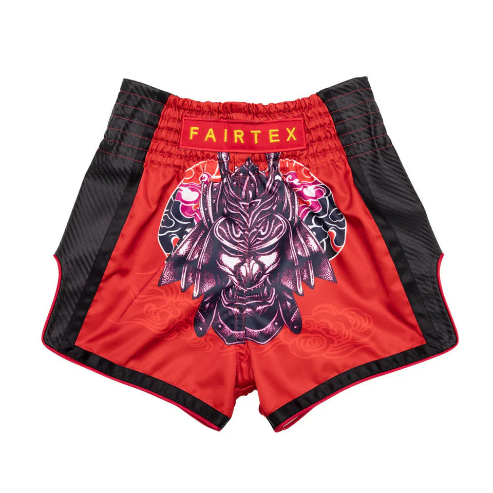 Red and black Fairtex shorts with a dragon design on a white background