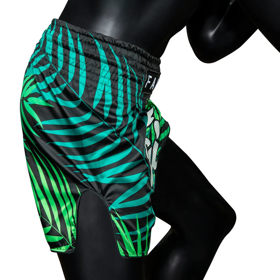 Green and black patterned Muay Thai shorts on a mannequin against a white background