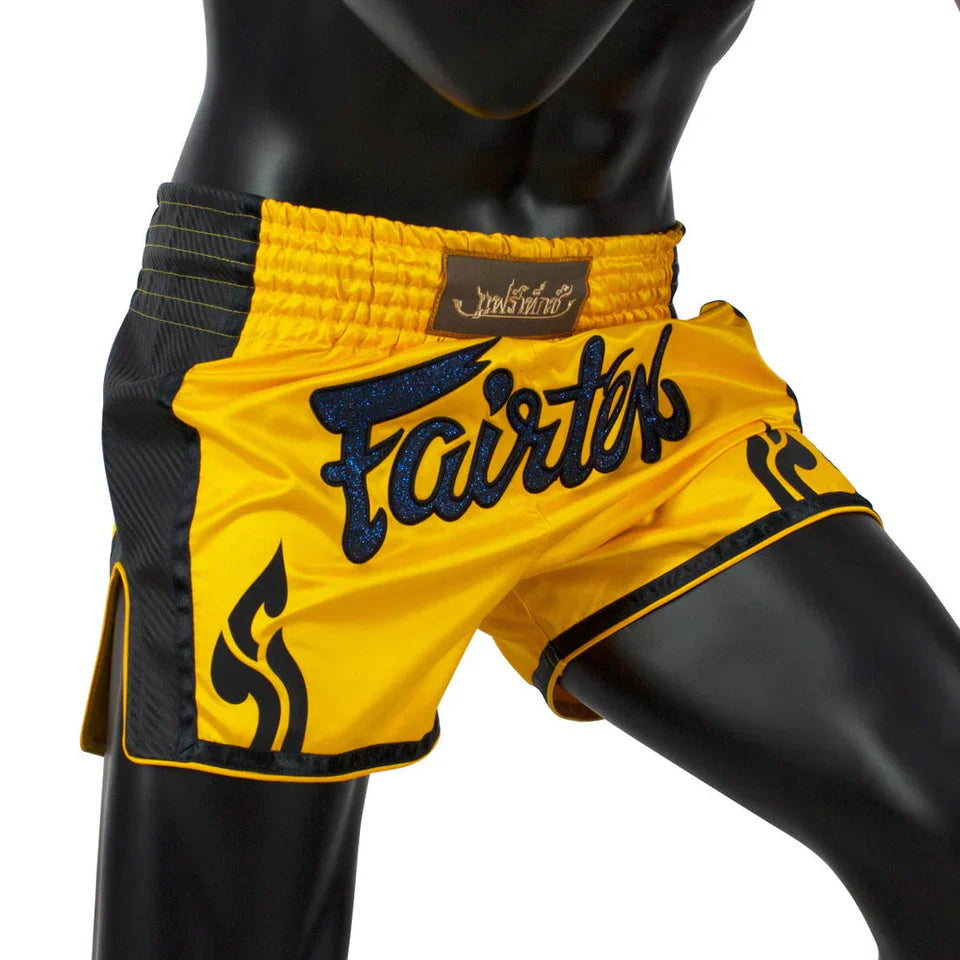Yellow and black Muay Thai shorts with 'Fairtex' branding on a mannequin.