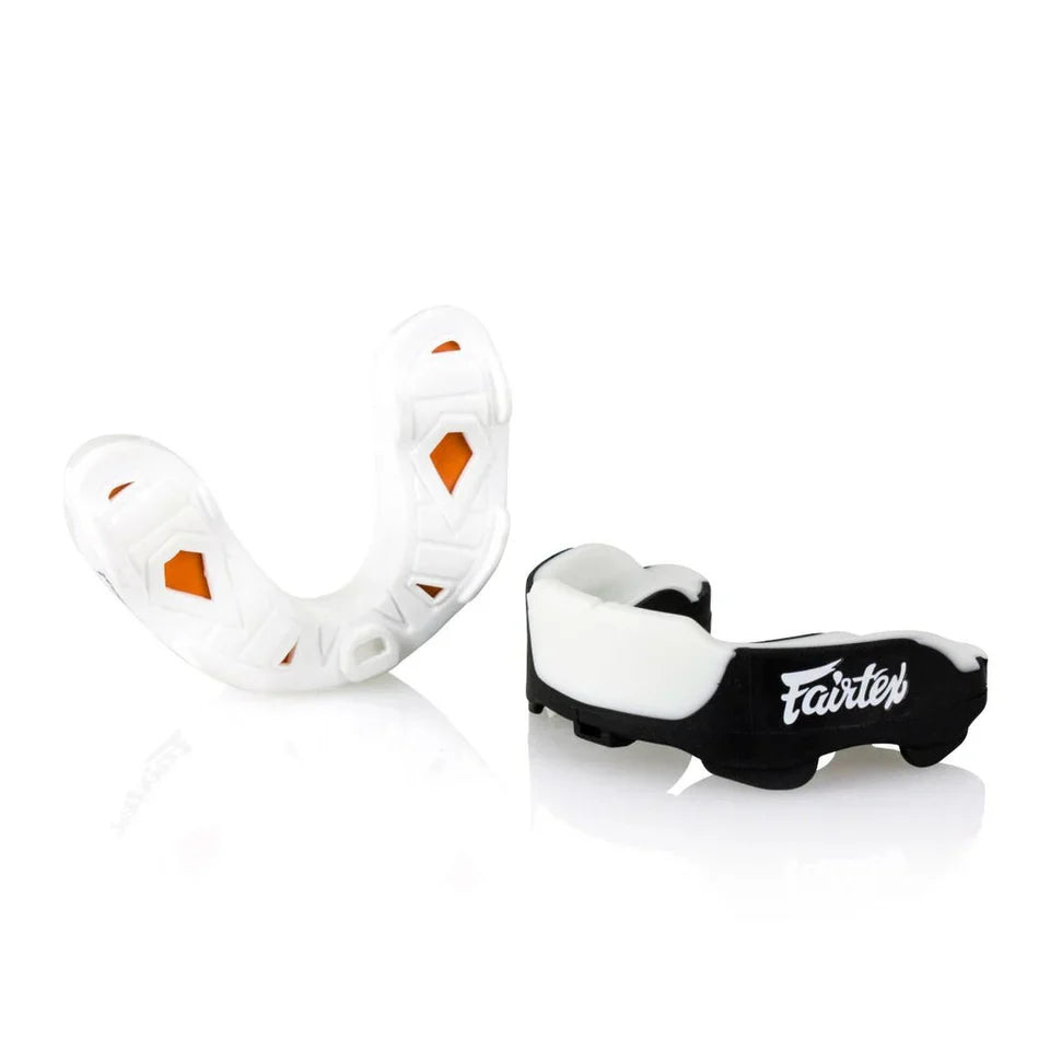 Two mouthguards, one white with orange accents and one black with 'Fairtex' branding, on a white background.