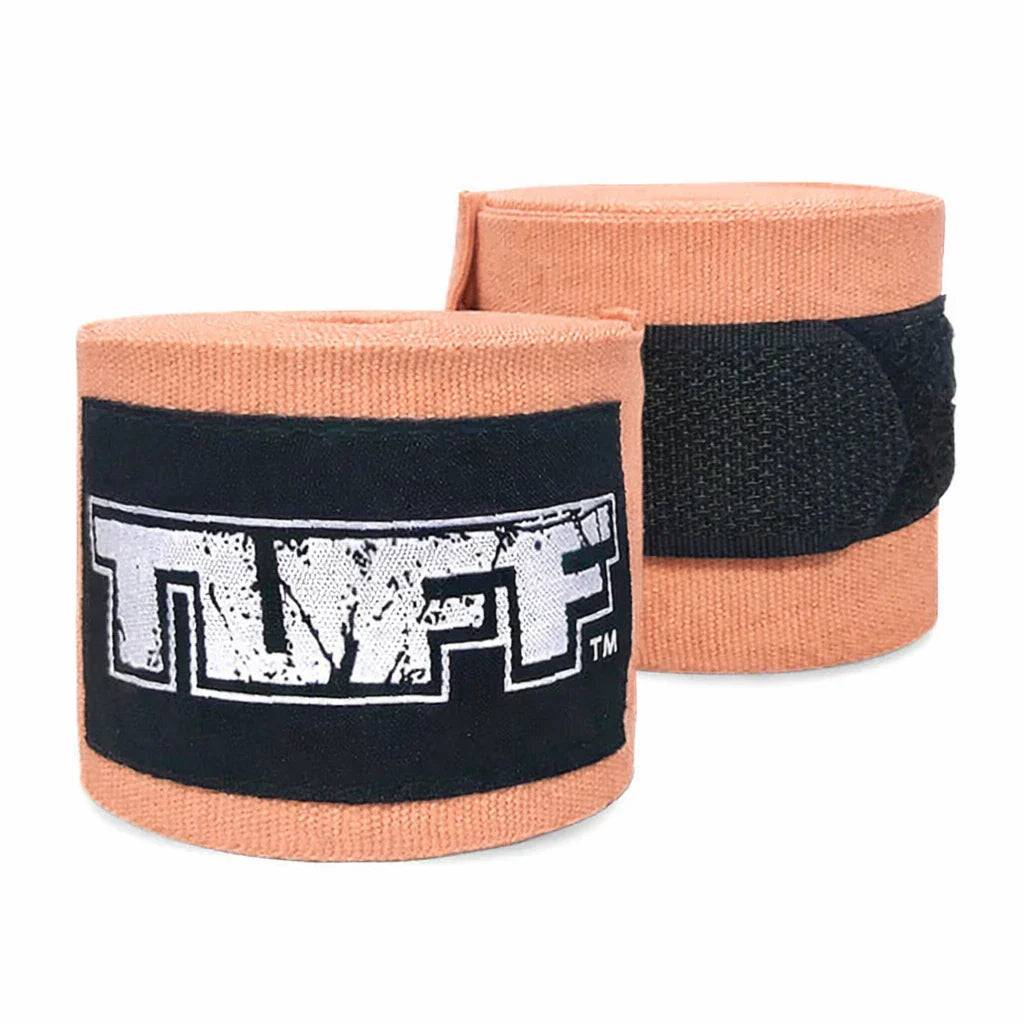 Pair of peach-colored boxing hand wraps with black bands featuring 'TUFF' logo on a white background.