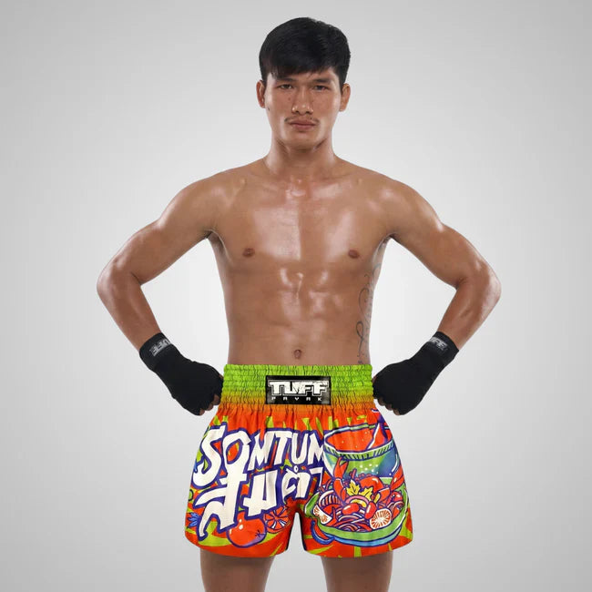 Man wearing colourful boxing shorts with visible branding on a gray background